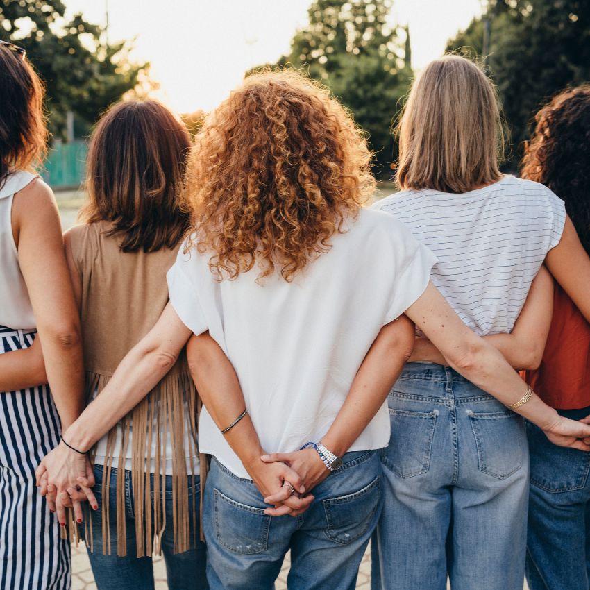Group of female friends with back to camera arms round each other